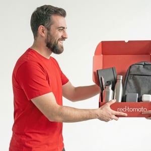 freepik_a-man-employee-sideview-wearing-red-and-black-polo-shirt-receiving-a-welcome-kit-containing-pen-notebook-drnking-bottles-backgpack-tech-like-powerbank-and-airpods-white-studio-background._0001-2
