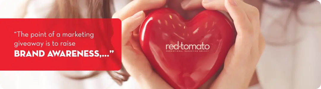Image of a girl holding a red heart with a message - Red Tomato. The point of a marketing giveaway is to raise brand awareness 